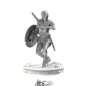 May include: A gray, detailed miniature figurine of a person in armor holding a sword and shield. The figurine is standing on a circular base with a decorative design.