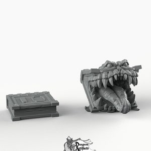 May include: A gray 3D printed book with a monster's mouth open, revealing sharp teeth and a long tongue. The book is closed and has a detailed design on the cover. The monster's mouth is open and the tongue is sticking out. The book is on a white background.