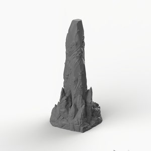 May include: A gray, 3D printed, detailed model of a tall, jagged, crystalline rock formation. The rock is textured and has a rough, uneven surface. The base of the rock is wider than the top, and the rock tapers to a point at the top.