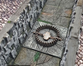 Pode incluir: Uma porta de armadilha de metal com uma roda circular de metal dentada. A porta de armadilha está colocada em um piso de pedra com uma parede de pedra de cada lado. A porta de armadilha faz parte de um conjunto de masmorra em miniatura.