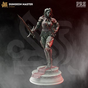 Könnte beinhalten: Eine detaillierte Miniaturfigur einer weiblichen Kriegerin in dunkler Rüstung, die ein Schwert und einen Kelch hält. Sie steht auf einem Steinsockel mit einem roten Teppich. Die Figur ist in Grün-, Braun- und Rottönen bemalt.