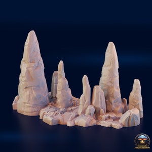 May include: A 3D printed miniature set of tall, thin, light brown rock formations. The rocks are arranged in a cluster on a base, creating a natural rock formation scene.