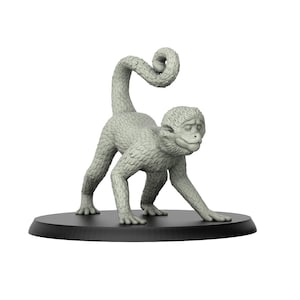 Puede incluir: Una pequeña figura de mono gris con la cola enroscada. El mono está de pie sobre una base circular negra.