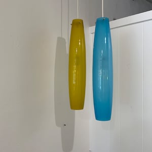May include: Two glass pendant lights hanging from the ceiling. The light on the left is yellow and the light on the right is blue.