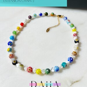 May include: A colorful beaded necklace with a variety of glass beads, including white, blue, green, yellow, red, and pink. The necklace is 15 inches long with a 2.5 inch extension chain.  LENGTH: 15" + 2.5" EXTENSION *FEEL FREE TO ASK FOR A LONGER EXTENSION CHAIN :)