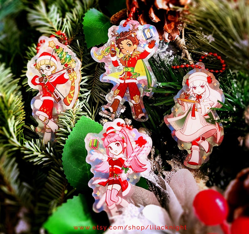 May include: Four Christmas-themed acrylic charms with cartoon characters in festive outfits. The charms are red, white, and gold, with a holographic effect. They are hanging on a background of pine needles and greenery. The text "www.etsy.com/shop/lilacknight" is visible.