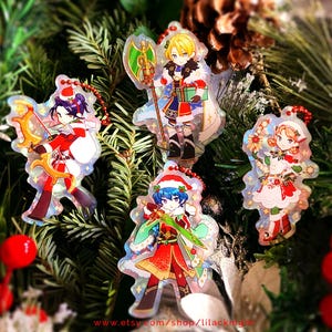 May include: Christmas-themed anime character acrylic charms. Each charm features a different character in festive attire, including Santa hats and holiday-themed weapons. The charms are on a Christmas tree background, with a website address at the bottom.