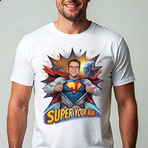 May include: White t-shirt featuring a superhero design with the text "SUPER YOUR NAME". The design includes a person in a superhero costume with a red cape, blue suit, and a yellow "J" on the chest. A cartoon planet is in the background.