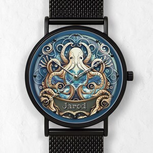May include: Black wristwatch with a blue face featuring a detailed octopus design. The watch face has a blue background with a white and gold octopus illustration. The watch band is black mesh, and the name "Jarod" is displayed on the face.