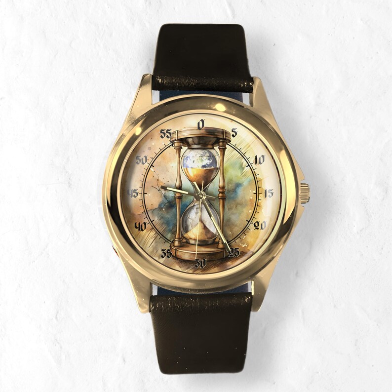K&ouml;nnte beinhalten: Goldfarbene Armbanduhr mit schwarzem Lederarmband. Das Zifferblatt zeigt ein Sanduhr-Design mit einem Globus im Inneren, vor einem Aquarellhintergrund. Die Uhr hat eine klassische runde Form mit Minutenmarkierungen.