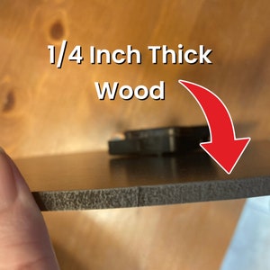 May include: Close-up of a dark brown wood piece, approximately 0.64 cm thick. The edge of the wood is textured, and the surface is smooth and reflective. White text reads "1/4 Inch Thick Wood" with a red arrow.