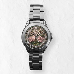 May include: A stainless steel wristwatch with a detailed tree of life design on the face. The watch features Roman numeral hour markers and a silver-toned metal band. The watch face displays a tree with pink and green accents.