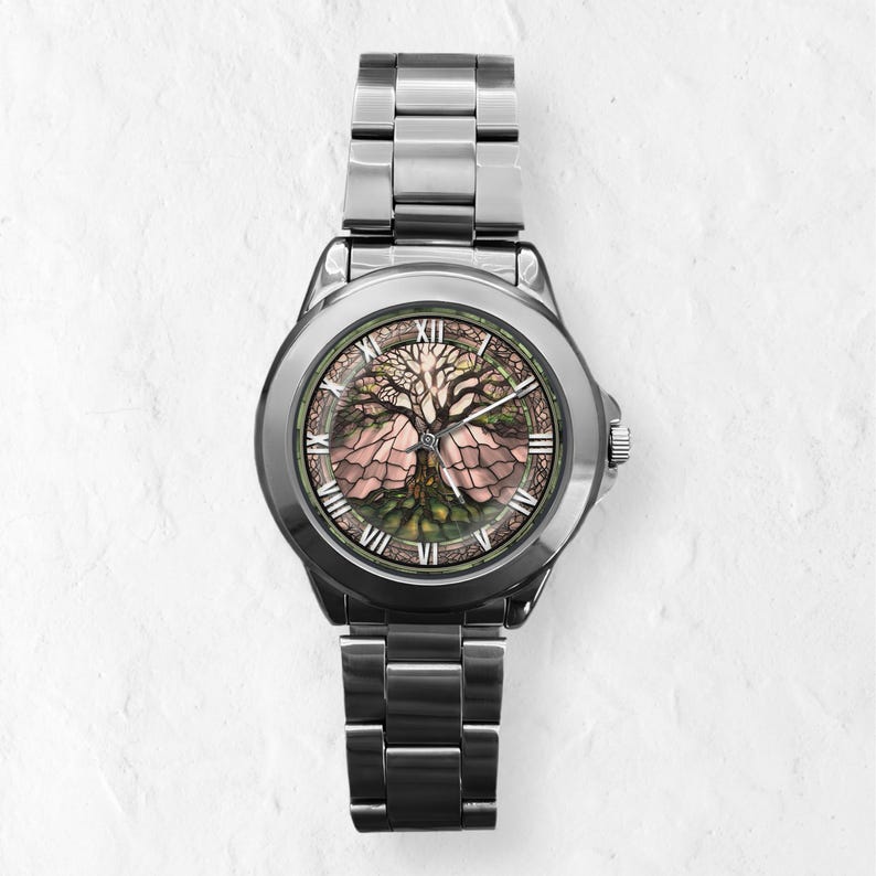May include: A stainless steel wristwatch with a detailed tree of life design on the face. The watch features Roman numeral hour markers and a silver-toned metal band. The watch face displays a tree with pink and green accents.