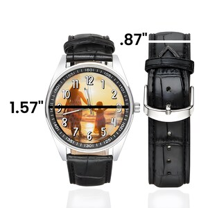 Puede incluir: Un reloj plateado con una correa de cuero negro. La esfera del reloj tiene una foto de una madre y un hijo en la playa. El reloj mide 4 cm de ancho y la correa 2,2 cm de ancho.