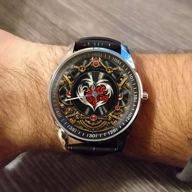 May include: A wristwatch with a black leather strap and a round silver case. The dial features a central heart graphic filled with red gears, surrounded by intricate gold-toned mechanical clockwork patterns, small red accents, and white hands.