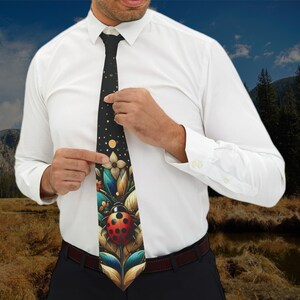 May include: A black tie with a colourful floral design featuring a large red ladybug. The background of the tie is black with white dots.