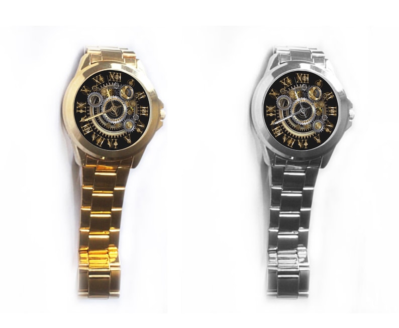 K&ouml;nnte beinhalten: Zwei Armbanduhren mit schwarzen Zifferbl&auml;ttern und goldenen r&ouml;mischen Ziffern als Stundenmarkierungen. Die Uhr links hat ein goldenes Armband, die Uhr rechts ein silbernes Armband.