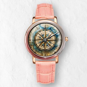 May include: A rose gold wristwatch with a light pink leather band. The watch face features a compass design with gold and blue accents. The watch has a silver bezel.