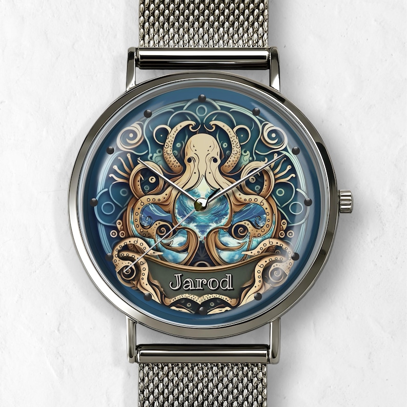 May include: A silver wristwatch with a mesh band and a blue face. The watch face features an octopus design in gold and cream colors, with the name "Jarod" displayed on a banner. The watch has a round face and a silver bezel.
