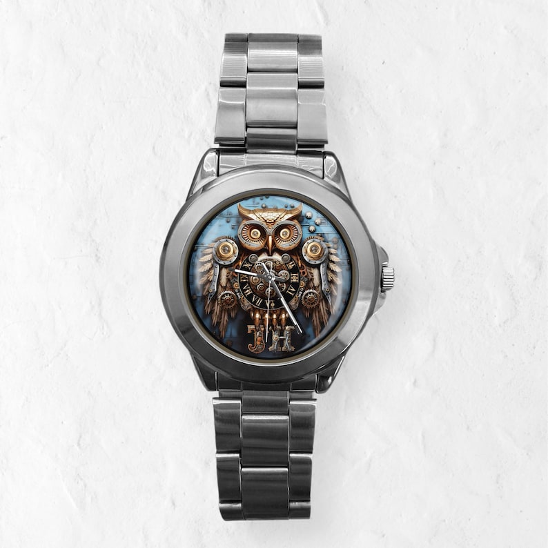 K&ouml;nnte beinhalten: Silberne Armbanduhr mit einem detaillierten Eulen-Design auf dem Zifferblatt. Die Eule ist in Gold-, Braun- und Bronzet&ouml;nen dargestellt, mit aufwendigen mechanischen Details. Sie hat ein silbernes Armband und einen blauen Hintergrund.