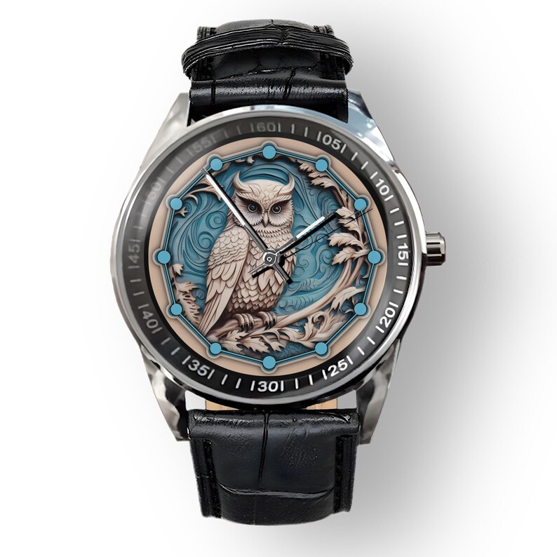May include: A silver wristwatch with a black leather strap. The watch face features a detailed owl design in white, blue, and beige. The watch has a round face with a black bezel and a textured black leather strap.