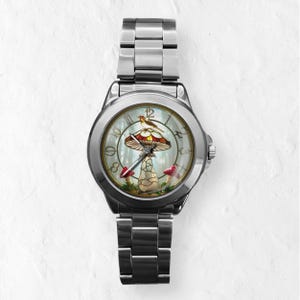 Puede incluir: Reloj de pulsera plateado con un dise&ntilde;o caprichoso de hongo en la esfera. La esfera del reloj presenta un hongo rojo y blanco con un p&aacute;jaro posado encima, sobre un fondo de bosque. El reloj tiene una correa de acero inoxidable.