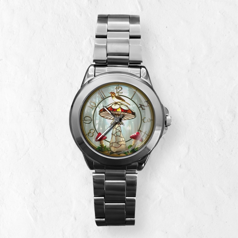 Puede incluir: Reloj de pulsera plateado con un dise&ntilde;o caprichoso de hongo en la esfera. La esfera del reloj presenta un hongo rojo y blanco con un p&aacute;jaro posado encima, sobre un fondo de bosque. El reloj tiene una correa de acero inoxidable.