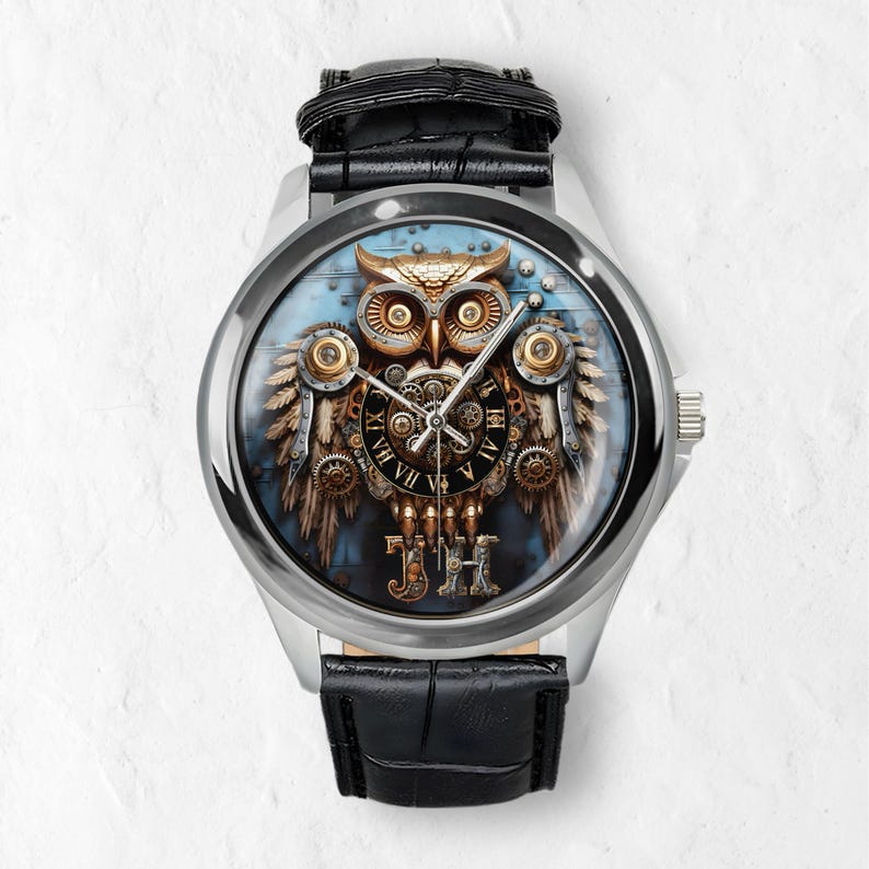 K&ouml;nnte beinhalten: Silberne Armbanduhr mit schwarzem Lederarmband. Das Zifferblatt zeigt ein detailliertes Steampunk-Eulen-Design mit Zahnr&auml;dern, r&ouml;mischen Ziffern und den Initialen "JH". Die Eule ist in Gold-, Bronze- und Braunt&ouml;nen vor blauem Hintergrund.