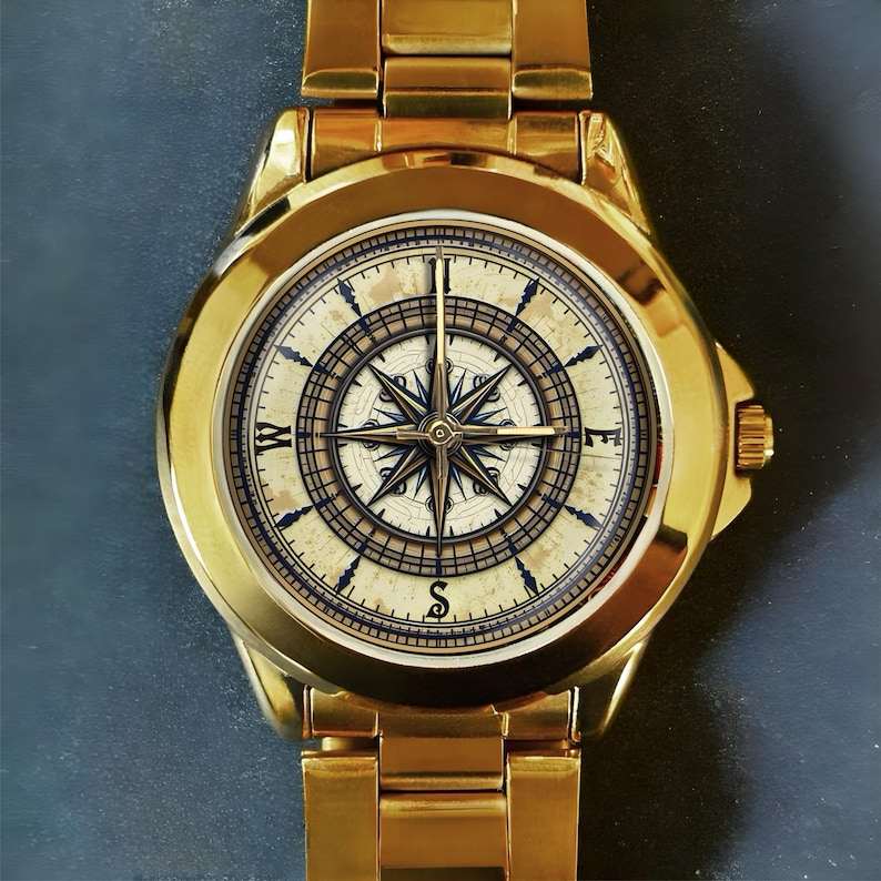 May include: Gold-toned wristwatch with a compass rose design on the face. The watch features a gold band and a round face with a detailed compass rose in shades of cream, blue, and gold. The watch is a classic accessory.