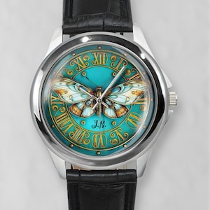 May include: A silver wristwatch with a black leather band. The watch face features a teal background with a butterfly design and gold Roman numerals. The initials "J.H." are at the bottom.