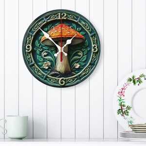 May include: A round wall clock with a mushroom design. The clock face features a detailed illustration of a mushroom with a red and orange cap, set against a green background with floral accents. The clock hands are white.