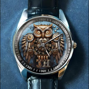 K&ouml;nnte beinhalten: Silberne Armbanduhr mit schwarzem Lederarmband. Das Zifferblatt zeigt ein detailliertes Steampunk-Eulen-Design mit Zahnr&auml;dern, Fl&uuml;geln und r&ouml;mischen Ziffern. Die Uhr hat eine goldfarbene Krone und eine schwarze L&uuml;nette mit wei&szlig;en Markierungen.