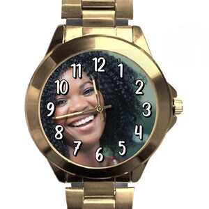 Puede incluir: Reloj de pulsera dorado con una foto en blanco y negro de una mujer sonriendo en la esfera. Los n&uacute;meros del 1 al 12 est&aacute;n impresos en negro en la esfera del reloj.