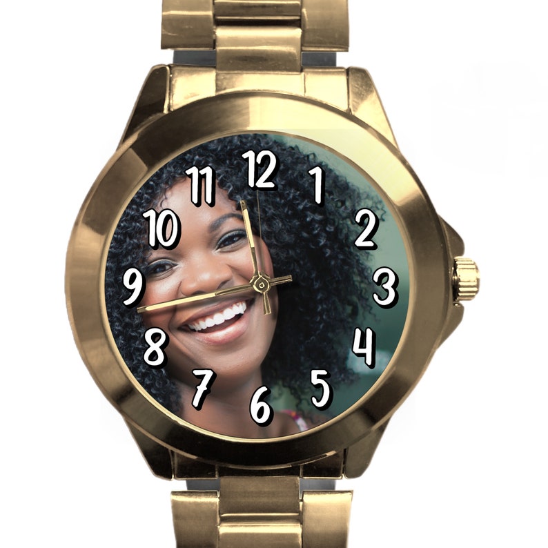 Puede incluir: Reloj de pulsera dorado con una foto en blanco y negro de una mujer sonriendo en la esfera. Los n&uacute;meros del 1 al 12 est&aacute;n impresos en negro en la esfera del reloj.