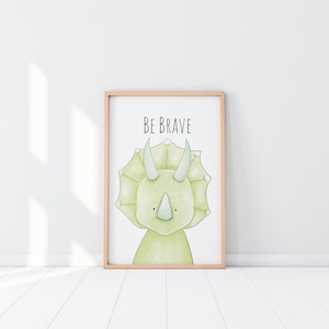 May include: A framed print with a green cartoon triceratops and the text "BE BRAVE" in black.