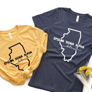 May include: Two t-shirts with a graphic of the state of Illinois and the text "Epsilon Sigma Alpha beta mu". The t-shirts are yellow and navy blue.