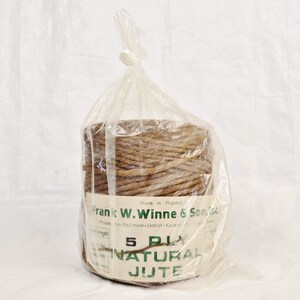 May include: A roll of brown 5-ply natural jute twine in a clear plastic bag. The label reads "Made in Thailand. Frank W. Winne & Son, Inc. Philadelphia - Baltimore - Detroit - Kansas City - Dallas".
