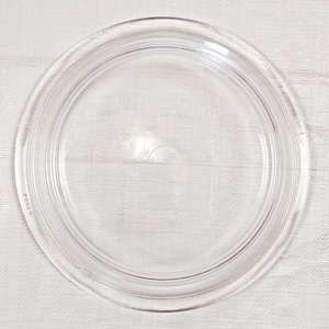 May include: A clear glass lid with a raised rim and the word "PYREX" printed on the side.