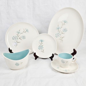 May include: A set of vintage blue and white floral patterned china dinnerware. The set includes a large oval platter, two dinner plates, a small bowl, a teacup and saucer.