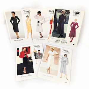 May include: A collection of five vintage Vogue sewing pattern envelopes featuring various garment designs by Ralph Lauren, Yves Saint Laurent, Christian Dior, and John Anthony. Each envelope displays illustrations of models wearing dresses, skirts, and jackets.