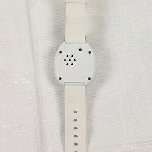 K&ouml;nnte beinhalten: Wei&szlig;e Armbanduhr mit rundem Zifferblatt und wei&szlig;em Armband. Die Uhr hat einen kleinen Lautsprecher auf der R&uuml;ckseite.