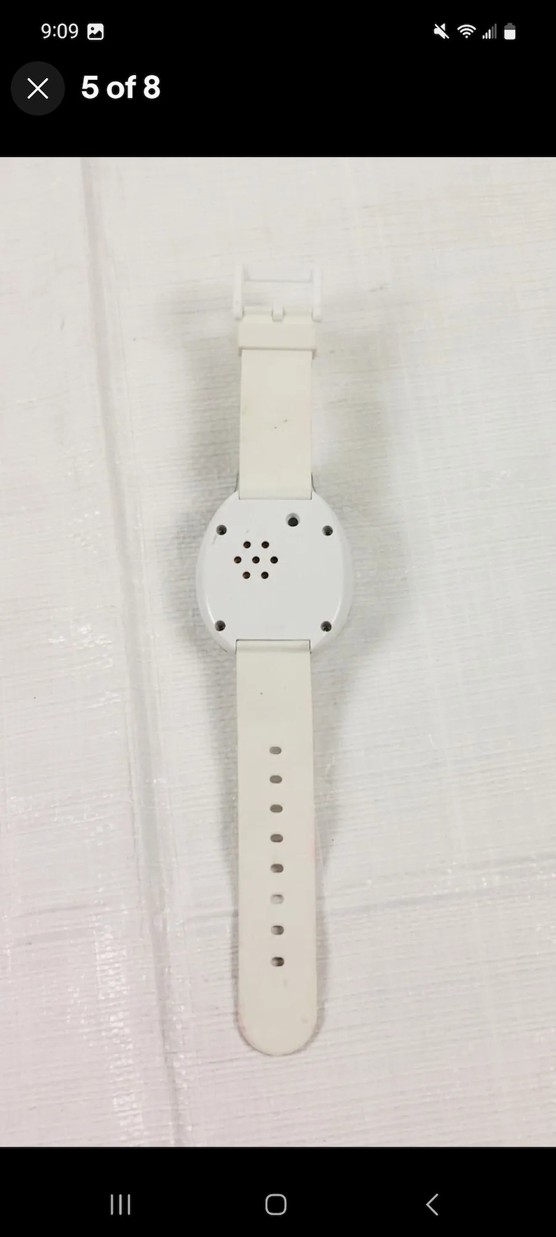 K&ouml;nnte beinhalten: Wei&szlig;e Armbanduhr mit rundem Zifferblatt und wei&szlig;em Armband. Die Uhr hat einen kleinen Lautsprecher auf der R&uuml;ckseite.