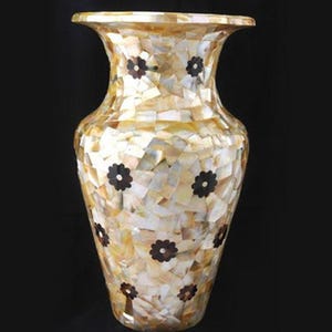 Op de afbeelding: Een decoratieve vaas met een uitlopende bovenkant en een bolvormig lichaam. De vaas is bedekt met een mozaïek van iriserende, rechthoekige stukken in crème, beige en goud. Donkerbruine bloemvormige accenten zijn gelijkmatig verdeeld.