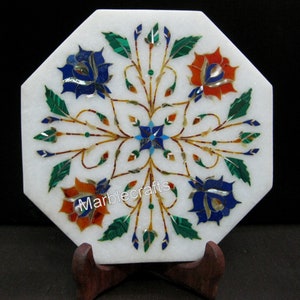 Peut inclure: Pièce décorative octogonale en marbre blanc avec un motif floral incrusté. Le motif présente des fleurs bleues, rouges et oranges, des feuilles vertes et un motif central en forme d'étoile. Le texte "marblecrafts" est visible.