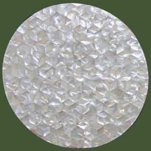 Op de afbeelding: Een rond, decoratief object met een mozaïekpatroon. Het oppervlak bestaat uit kleine, iriserende, kubusvormige stukjes, waardoor een glinsterend, gestructureerd effect ontstaat. De kleur is voornamelijk wit met hints van zilver en parelmoer.