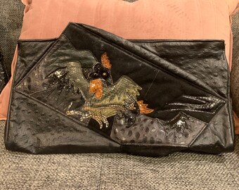 Black leather, suede, and snake skin over sized abstract clutch with Phoenix bird on the front.