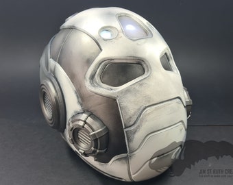Puede incluir: Un casco impreso en 3D blanco y gris con un diseño futurista. El casco tiene una luz en la parte superior y una superficie texturizada.
