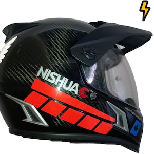 Könnte beinhalten: Schwarzer Motorradhelm mit einer Karbonfaser-Schale und einem klaren Visier. Der Helm hat einen roten und weißen Aufkleber mit dem Wort "NISHUA" darauf.