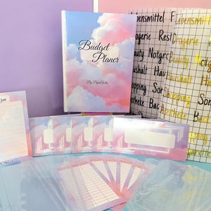 Könnte beinhalten: Ein Budgetplaner-Set mit Wolken-Design in Rosa und Blau. Das Set enthält ein Notizbuch, Notizblöcke, Umschläge und transparente Kunststoffhüllen. Auf dem Notizbuch steht "Budget Planer" und "By Pippel Witte".