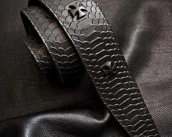 May include: Black leather guitar strap with a snakeskin pattern and cross-shaped metal accents.
